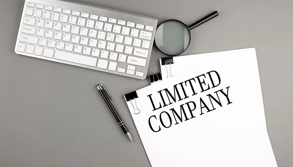 keyboard, magnifying glass, pen and a piece of paper with "Limited Company" written down