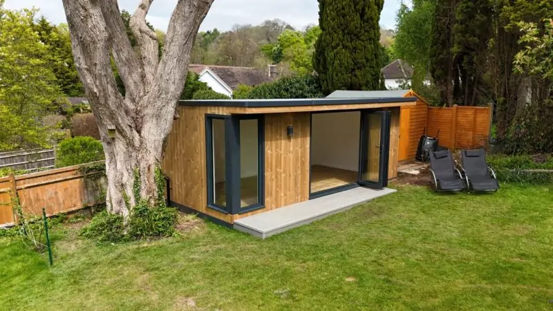 garden office, next to tree on green grass with open doors