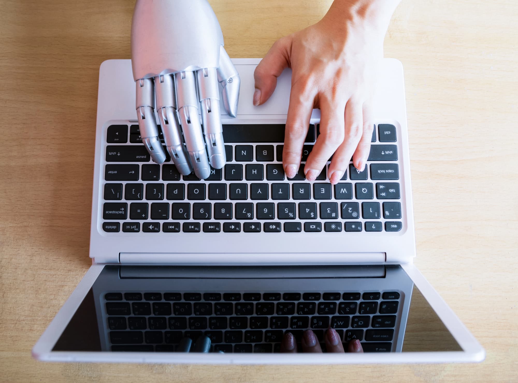robot hand and human hand on laptop